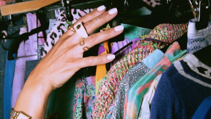 A person reaching for clothes made of plant wool in a thrift shop