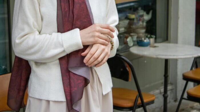A woman wearing a plant wool jumper standing outside a coffee shop