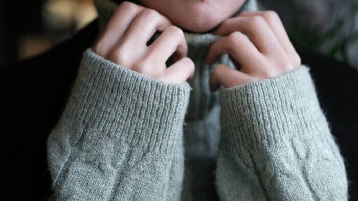 A woman wearing a thick grey jumper made of plant wool