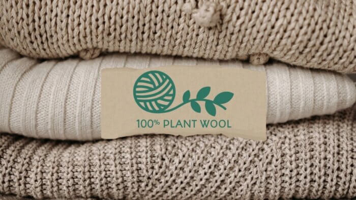 Three beige and white jumpers made of plant wool in a pile