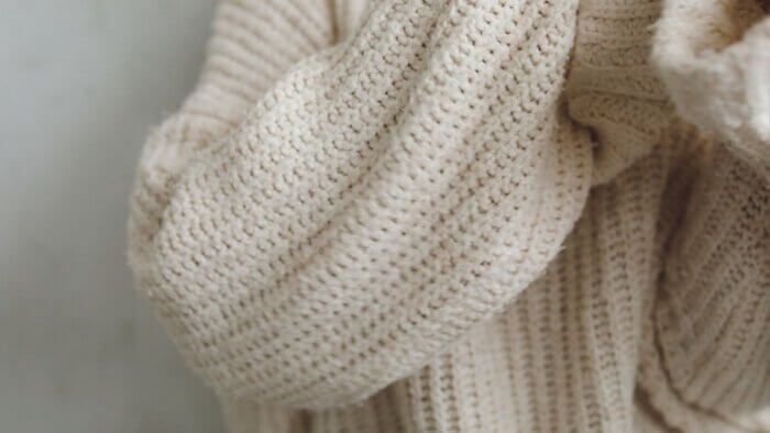 A close-up of a woman wearing a cream jumper